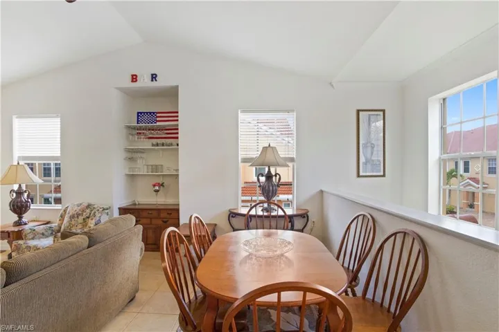 Dining space featuring vaulted ceiling, healthy amount of natural light, light tile patterned flooring, and crown molding