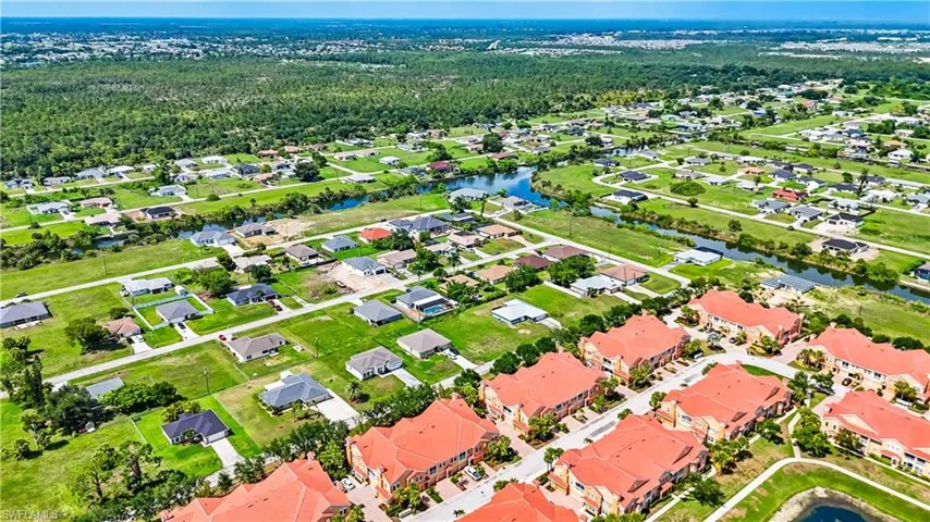 Aerial perspective of suburban area featuring a large body of water and a forest