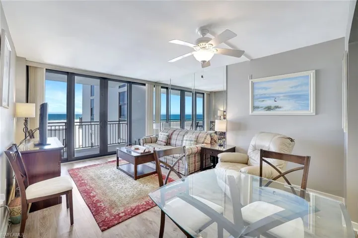 Living area with ceiling fan, plenty of natural light, wood finished floors, and baseboards