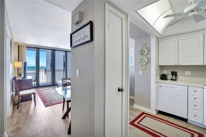 Kitchen featuring white dishwasher, a water view, light wood-type flooring, white cabinetry, and light countertops
