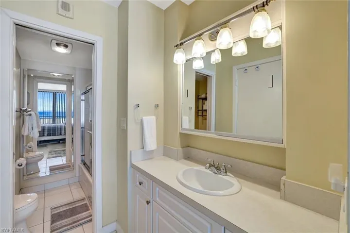 Bathroom with toilet, vanity, a shower with shower door, and tile patterned flooring