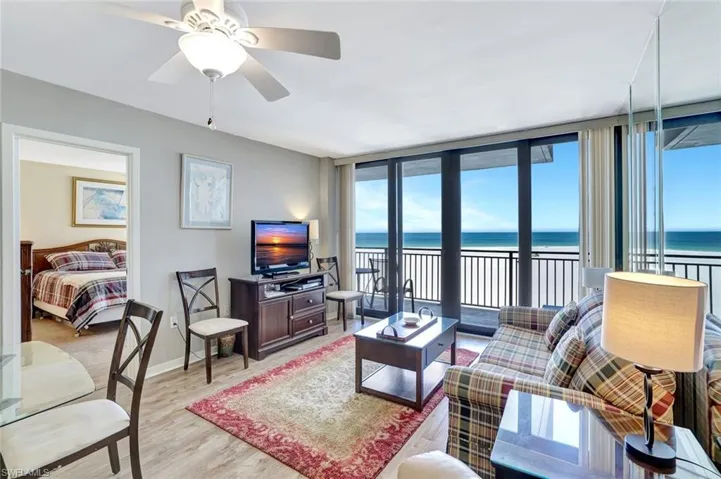 Living area with light wood finished floors, a wall of windows, a ceiling fan, and baseboards