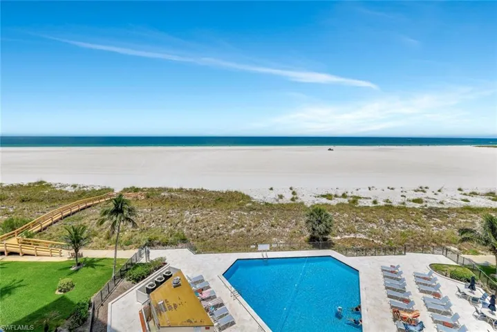 Community pool featuring view of water and beach