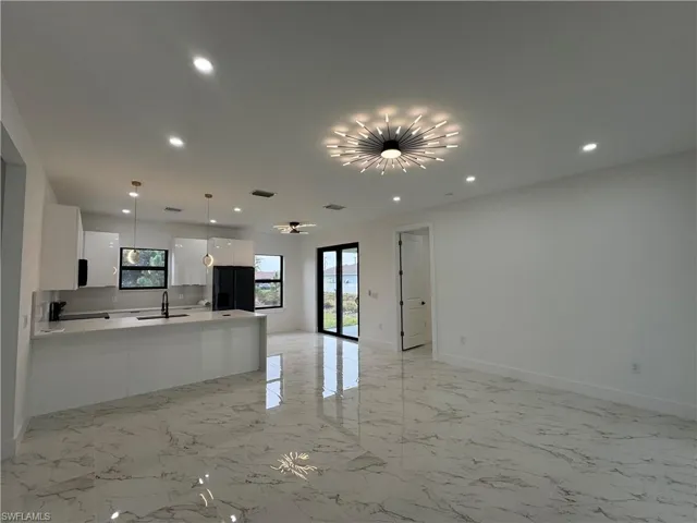 Kitchen with white cabinetry, sink, black refrigerator with ice dispenser, and decorative light fixtures