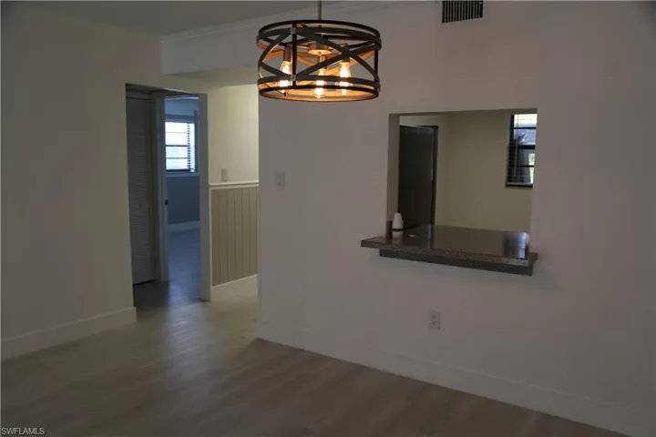 Unfurnished dining area with wood finished floors, ornamental molding, and suspended lighting