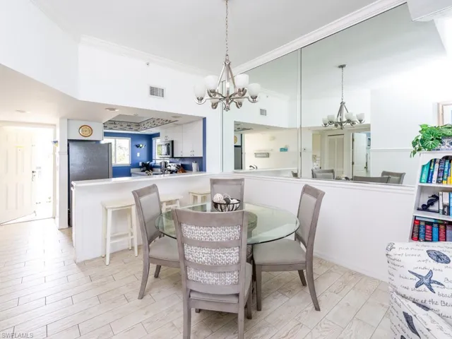 Dining space with light wood-type flooring, ornamental molding, and a chandelier