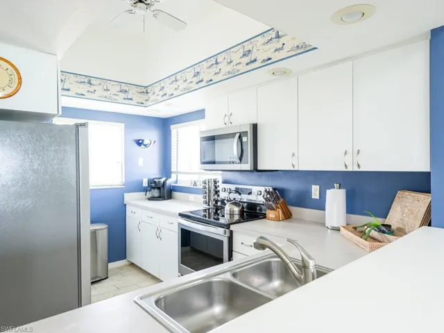 Kitchen featuring stainless steel appliances, white cabinetry, and light countertops