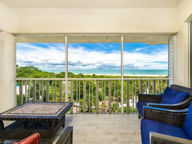 Sunroom / solarium with view of water and beach and wood finish floors