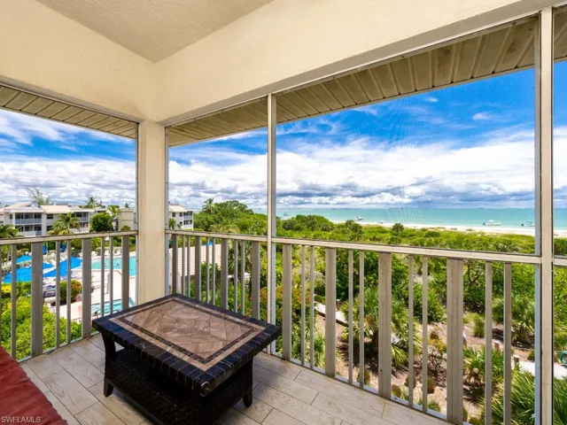 Balcony with view of pool and view of water and beach