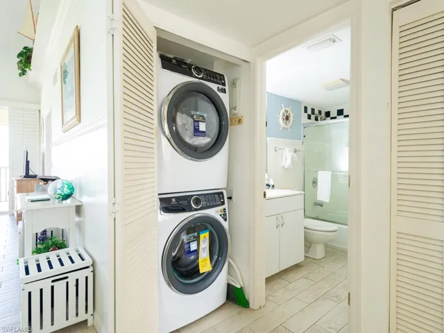 Washroom with wood tiled floors and estacked washer and dryer