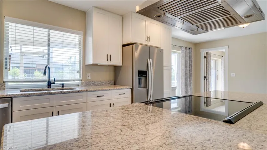 Kitchen featuring stainless steel appliances,white cabinets, sink, and ventilation hood