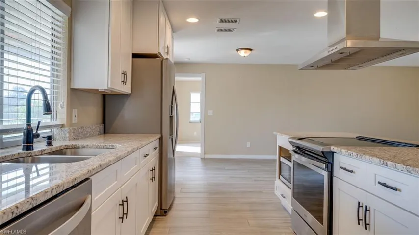 Kitchen featuring a wealth of natural light, ventilation hood and granite countertops