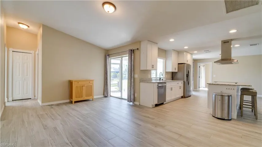 Kitchen with stainless steel appliances, island range hood, white cabinets, and a kitchen breakfast bar
