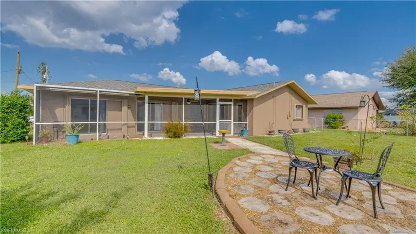 Rear view of house featuring a lawn, a patio, and a screened lanai