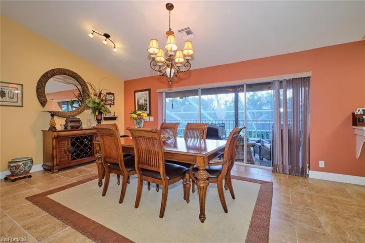 Tiled dining space featuring rail lighting and a chandelier