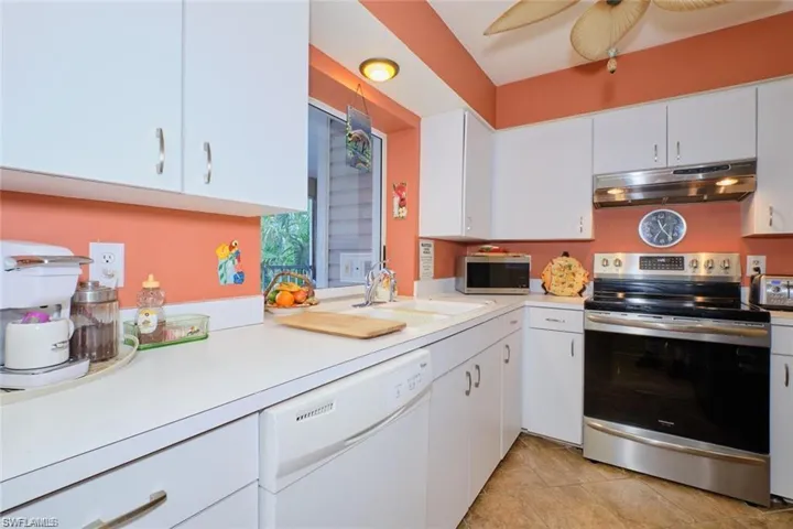Kitchen featuring ceiling fan, stainless steel appliances, white cabinets, sink, and light tile patterned floors