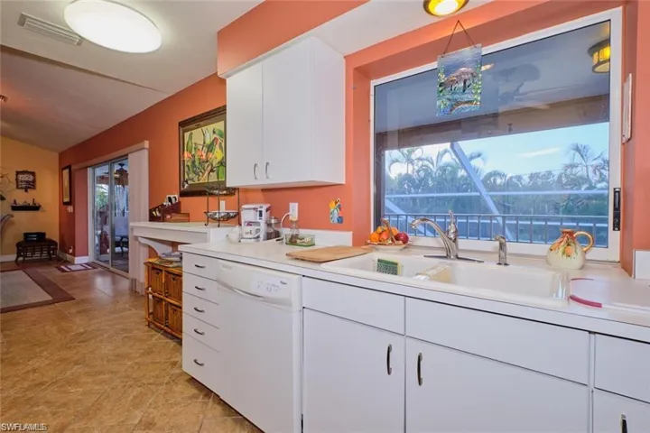 Kitchen featuring a healthy amount of sunlight, sink, white cabinetry, and white dishwasher