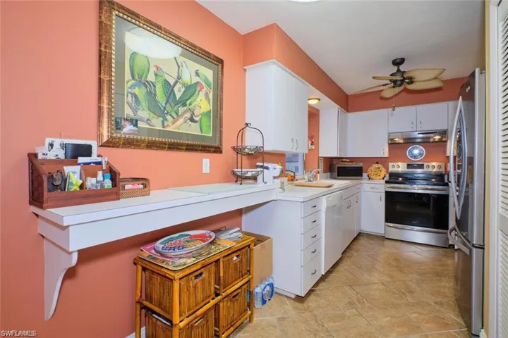 Kitchen featuring light tile patterned flooring, ceiling fan, white cabinets, sink, and appliances with stainless steel finishes