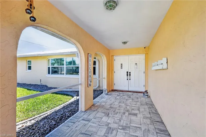 Covered entryway with patterned tile flooring, dual entry doors, and overhead lighting fixtures