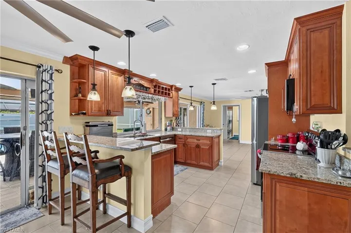 Kitchen featuring wood cabinetry, granite countertops, tile flooring, pendant lighting, and recessed lighting