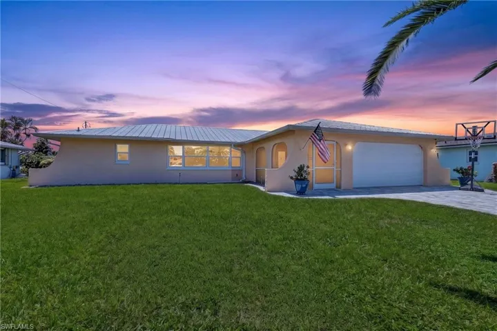 Stucco exterior with a metal roof, attached garage, and a paver driveway