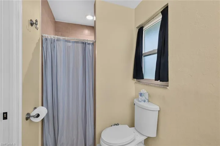 Shower with tiled surround, recessed lighting, and a frosted window