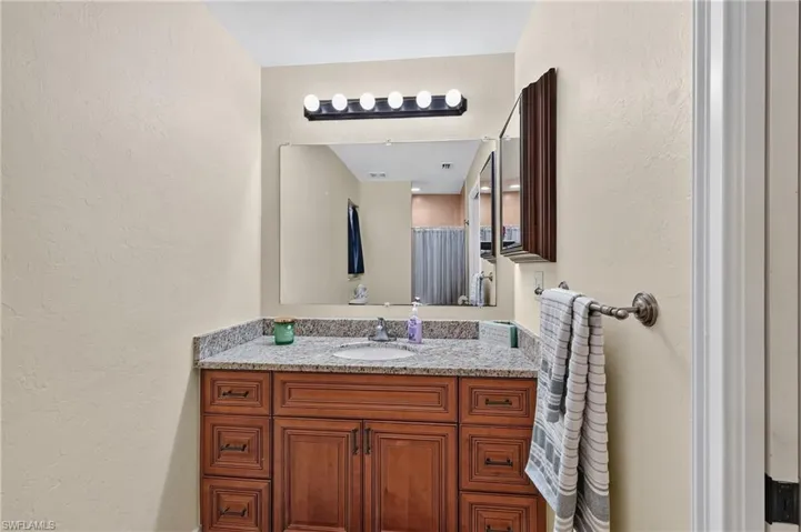 Wood-finish vanity with drawer storage, granite-style countertop, and an integrated sink