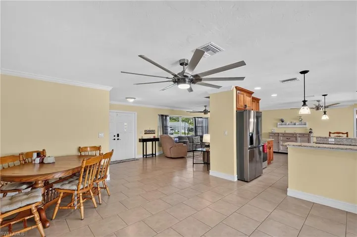 Spacious open concept - This could be used as living area to be open to kitchen interior featuring large format tile flooring, crown molding, and multiple ceiling fans