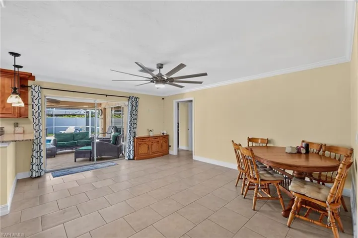 Spacious open concept - This could be used as living area to be open to kitchen - Neutral tone ceramic tile flooring, crown molding, and a large ceiling fan with integrated lighting