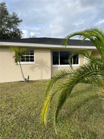 View of side of property featuring stucco siding and a lawn