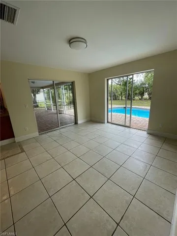 Spare room featuring light tile patterned floors, visible vents, and baseboards