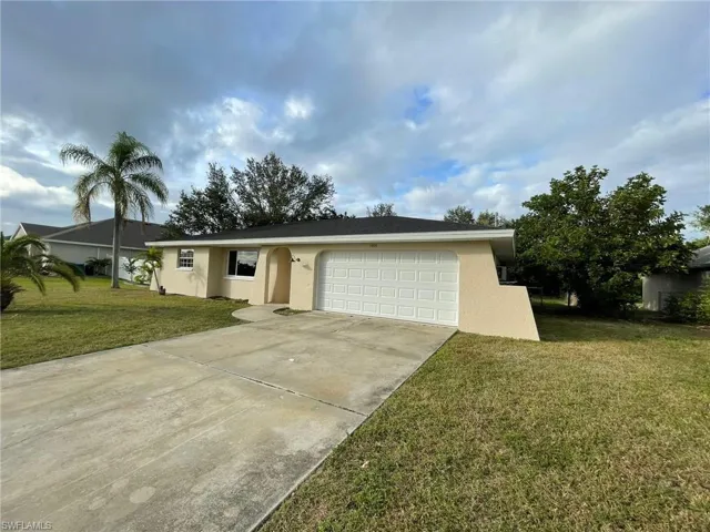 Ranch-style home featuring a front lawn, an attached garage, concrete driveway, and stucco siding