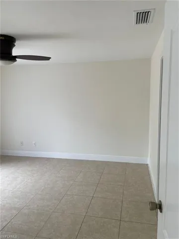 Empty room with tile patterned flooring, baseboards, visible vents, and ceiling fan