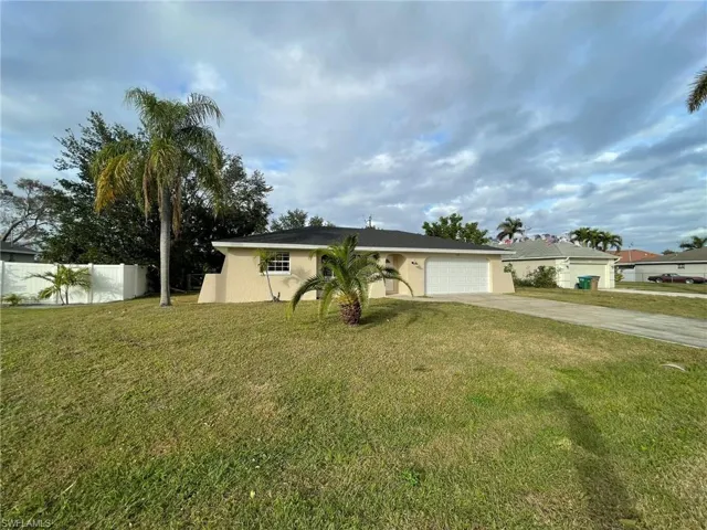 Single story home with fence, concrete driveway, a front yard, stucco siding, and a garage