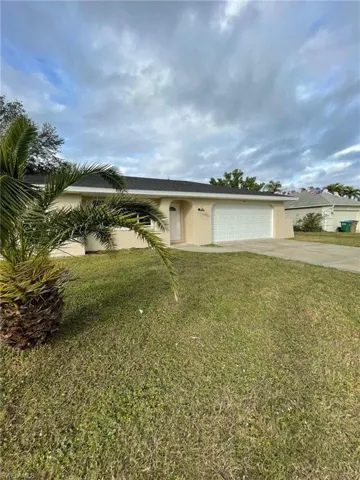 View of front of home featuring stucco siding, an attached garage, concrete driveway, and a front yard