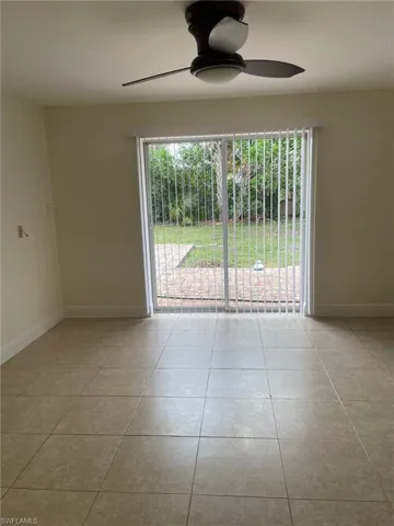 Empty room with tile patterned floors, plenty of natural light, a ceiling fan, and baseboards