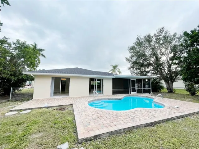 View of swimming pool featuring a patio area, fence, a lawn, and a sunroom