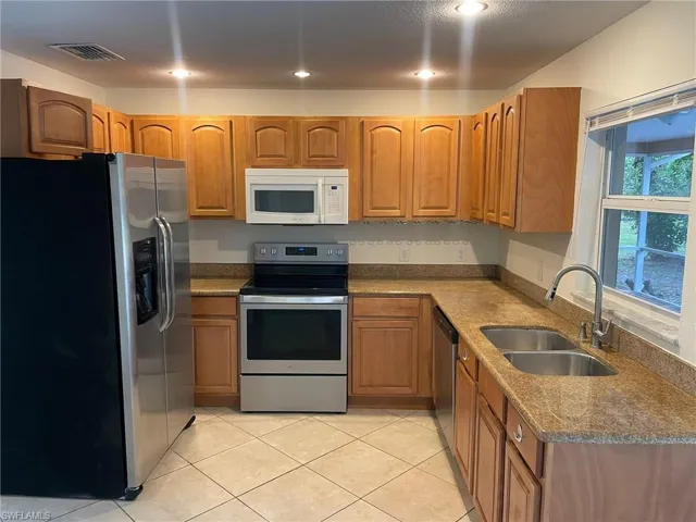 Kitchen featuring a sink, stainless steel appliances, visible vents, and brown cabinetry