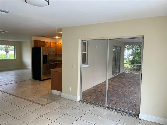 Kitchen featuring visible vents, baseboards, stainless steel fridge with ice dispenser, light tile patterned floors, and brown cabinets
