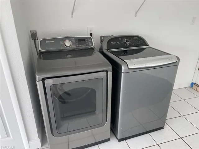 Laundry area featuring washer and dryer, light tile patterned flooring, and laundry area