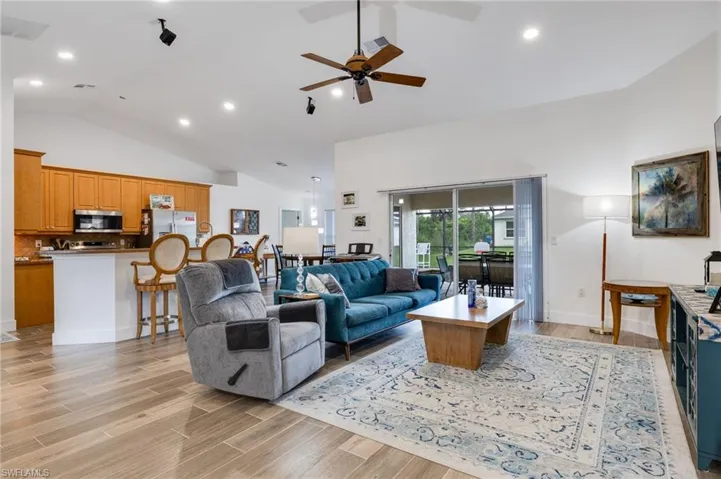 Living room and kitchen areas showing vaulted ceilings, wide-open area and sliders to the lanai.