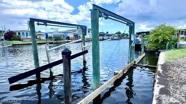 Waterfront property featuring a boat lift with wooden pilings and a concrete seawall