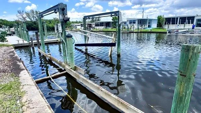 Waterfront property featuring a private boat dock with multiple pilings and a boat lift