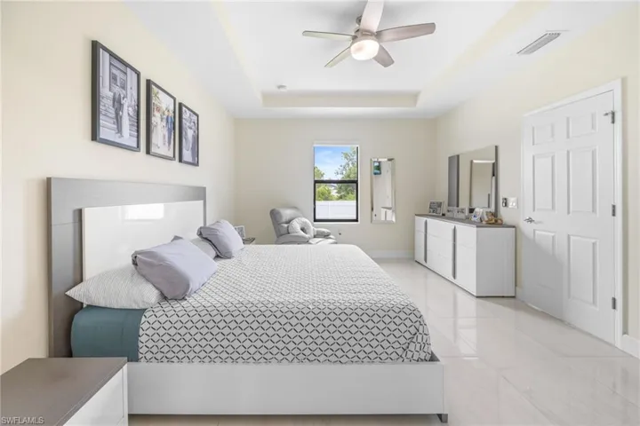 Bedroom featuring a raised ceiling, ceiling fan, and light tile patterned floors