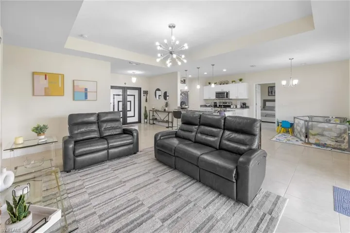 Living area with a chandelier, a raised ceiling, and light tile patterned flooring