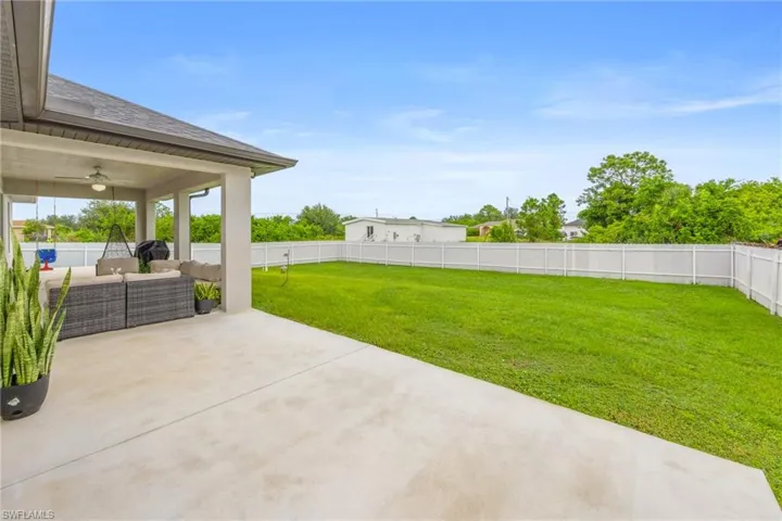 Fenced backyard featuring a patio area, an outdoor living space, and a ceiling fan