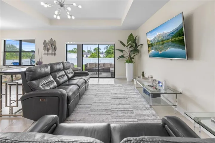 Living room featuring a tray ceiling, a chandelier, and light tile patterned flooring