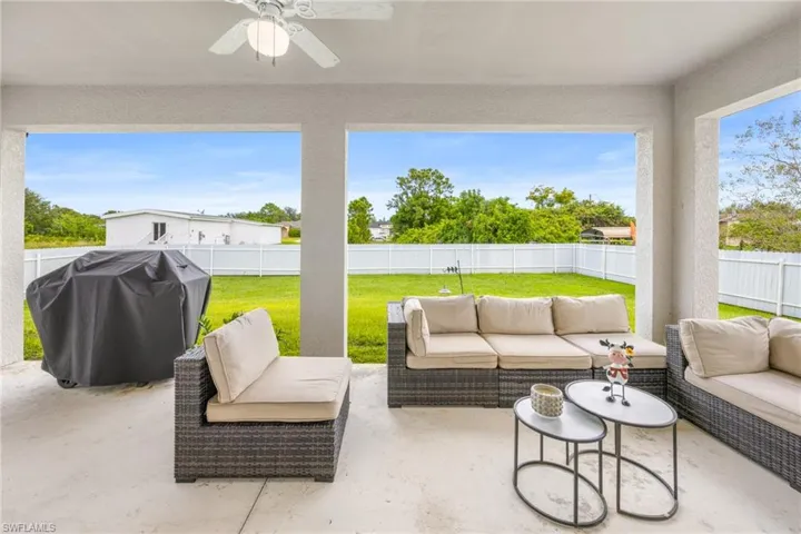 Fenced backyard featuring a patio area, grilling area, a ceiling fan, and an outdoor hangout area