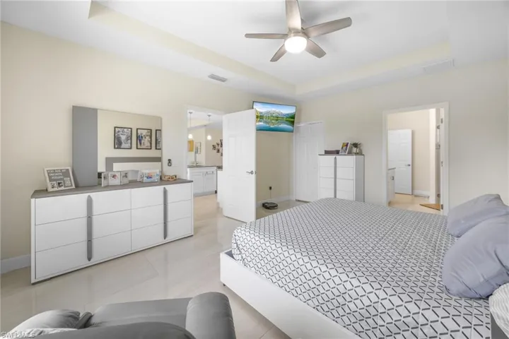 Bedroom featuring a raised ceiling, a ceiling fan, and light tile patterned flooring