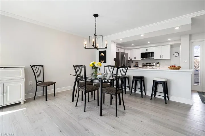 Dining room with an inviting chandelier, light hardwood / wood-style flooring, and ornamental molding